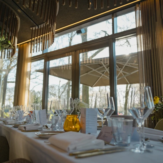 Gedekte tafel bij het raam in Brasserie Jacob van Bijstervelt, met de houten plafondconstructie en zicht op het terras