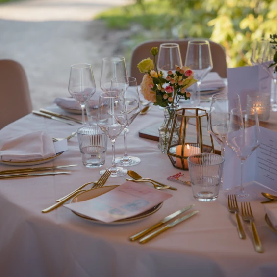 Buiten gedekte tafel met roze tafellinnen, gouden bestek, bloemen en waxinelichtjes op het landgoed